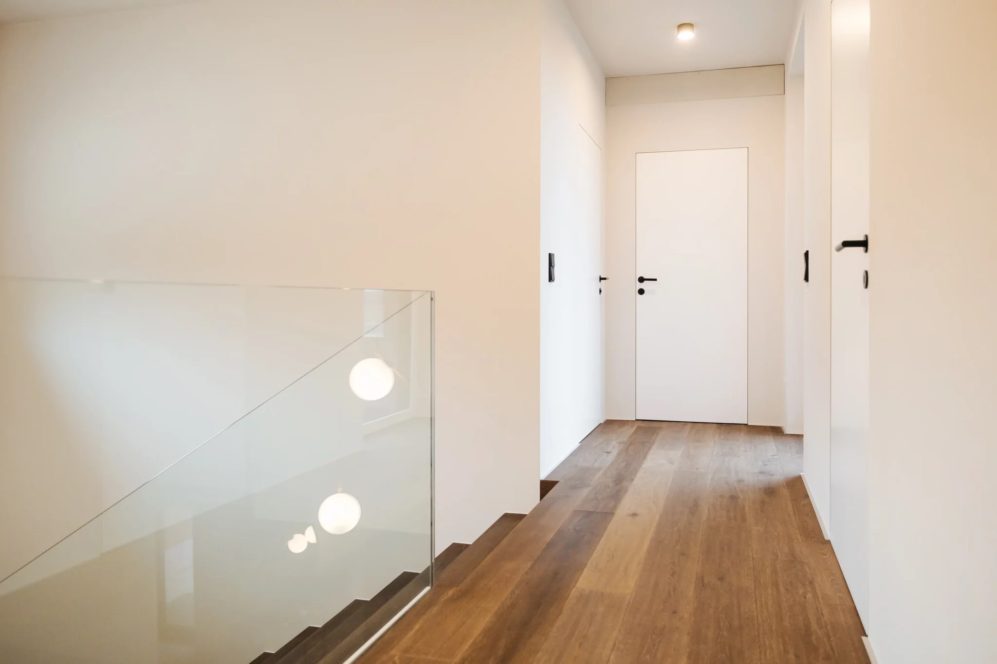 Weisse Tür (zargenlos im Vorzimmer und einer Glastreppe) mit SmartLock Drücker